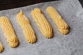 Raw eclairs choux pastry on the baking tray