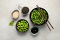 Raw edamame soya beans with salt and sauce on light gray background