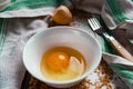 Raw egg broken into a white bowl with yolk and protein, next to the shell, fork and towel on a rusty metal background Royalty Free Stock Photo