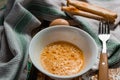 Raw egg broken into a white bowl with yolk and protein, next to the shell, fork and towel on a rusty metal background as at home i Royalty Free Stock Photo