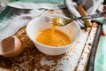 Raw egg broken into a white bowl with yolk and protein, next to the shell, fork and towel on a rusty metal background as at home i Royalty Free Stock Photo