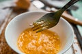 Raw egg broken into a white bowl with yolk and protein, next to the shell, fork and towel on a rusty metal background as at home i Royalty Free Stock Photo