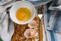 Raw egg broken into a white bowl with yolk and protein, next to the shell, fork and towel on a rusty metal background Royalty Free Stock Photo