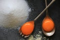 Raw egg yolk on a metal spoon. Ingredients for the cake: sugar, almond flour, cinnamon, eggs.