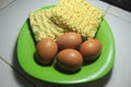 Raw eggs and dry instant noodles before cooking are on a plate. Royalty Free Stock Photo