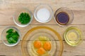 Raw eggs and ingredients on wooden background.