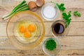 Raw eggs and ingredients on wooden background.