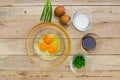 Raw eggs and ingredients on wooden background.