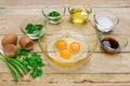 Raw eggs and ingredients on wooden background.