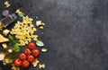 Raw farfolle with tomato and basil on a black background. Top view. Ingredients for making pasta Royalty Free Stock Photo