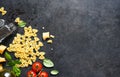 Raw farfolle with tomato and basil on a black background. Top view. Ingredients for making pasta Royalty Free Stock Photo