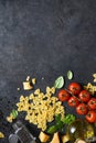 Raw farfolle with tomato and basil on a black background. Top view. Ingredients for making pasta Royalty Free Stock Photo