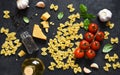 Raw farfolle with tomato and basil on a black background. Top view. Ingredients for making pasta Royalty Free Stock Photo