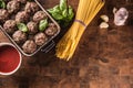 Raw feef meat balls basil tomato sauce garlic and spaghetti on butcher board Royalty Free Stock Photo