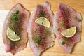 Raw fish fillet of tilapia on a cutting Board with lemon and spices