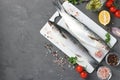 Raw fish mullet with ingredients and seasonings on white plastic board on dark background with place for text. Top view Royalty Free Stock Photo