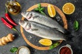 raw fish sea bass with ingredients on a dark background. banner, menu, recipe place for text, top view Royalty Free Stock Photo