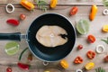 Raw fish steak on black frying pan