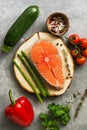 Raw fish steak salmon with fresh vegetables, asparagus, zucchini, sweet peppers, tomatoes, herbs and spices on a gray background. Royalty Free Stock Photo