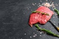 Raw Flat iron steak with rosemary and pink salt. Fresh Marble beef meat black Angus. Black background. Top view. Copy space Royalty Free Stock Photo