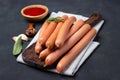 Raw frankfurter sausages with ketchup on cutting board