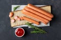 Raw frankfurter sausages with ketchup on cutting board