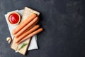 Raw frankfurter sausages with ketchup on cutting board