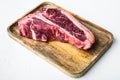 Raw fresh dry aged beef T-bone steak, on wooden tray, on white stone  background Royalty Free Stock Photo