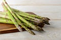 Raw fresh green asparagus stalks on a brown cutting board over a white wood kitchen table. Ingredient for healhy eating, Royalty Free Stock Photo