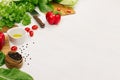 Raw fresh green vegetables, greens, red cherry tomatoes and kitchenware on soft white wood board, border. Royalty Free Stock Photo