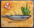 Raw fresh grey mullet fish lies on light wooden cutting board wi Royalty Free Stock Photo