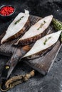 Raw fresh halibut fish steak on a wooden cutiing board. Black background. Top view Royalty Free Stock Photo