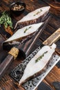 Raw fresh halibut fish steak on a wooden cutiing board. Black background. Top view Royalty Free Stock Photo