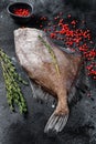 Raw fresh John Dory fish with pink pepper and thyme. Black background. Top view