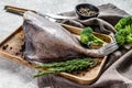 Raw fresh John Dory fish on a wooden tray with rosemary and broccoli. Gray background. Top view