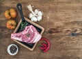 Raw fresh meat ribeye steak with pepper, salt, chili, garlic, spinach, heirloom tomatoes and rosemary in cooking pan