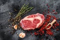 Raw fresh meat Ribeye Steak with seasoning. Rib eye beef steak. black background. top view