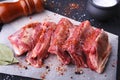 Raw fresh meat, uncooked lamb or beef ribs with pepper, garlic, salt, bay leaves and spices on dark stone background Royalty Free Stock Photo