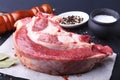 Raw fresh meat, uncooked lamb or beef ribs with pepper, garlic, salt, bay leaves and spices on dark stone background Royalty Free Stock Photo