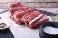 Raw fresh meat, uncooked lamb or beef ribs with pepper, garlic, salt and spices on dark stone background, Ready for Royalty Free Stock Photo