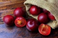 Raw and fresh organic plums inside rustic fabric bag on wooden table