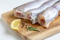 Raw fresh pollock fish on a wooden board with lemon
