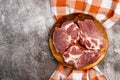 Raw fresh pork neck meat steaks on a round wooden cutting board on a dark grey background Royalty Free Stock Photo