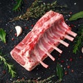 Raw fresh rack of lamb with green herbs.