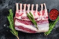 Raw fresh rack of lamb meat on marble board. Black background. Top view