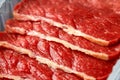 Raw fresh sizzling beef steak slices in plastic tray in butcher`s shop on dark background table