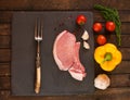 Raw fresh uncooked Pork meat steak on bone on slate stone chopping board block on wooden background. Ready for cooking. Royalty Free Stock Photo