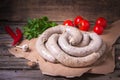 Raw fresh white sausages on a craft paper with vegetables. Weisswurst in a heap. Traditional Bavarian or Munich white sausage made