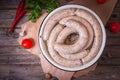 Raw fresh white sausages on a plate with vegetables. Weisswurst in a heap. Traditional Bavarian or Munich white sausage made from