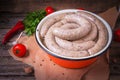 Raw fresh white sausages on a plate with vegetables. Weisswurst in a heap. Traditional Bavarian or Munich white sausage made from